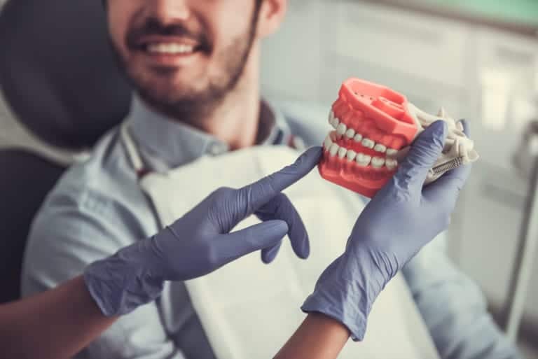 Dentist holding a dental model with implants, demonstrating dental restoration.